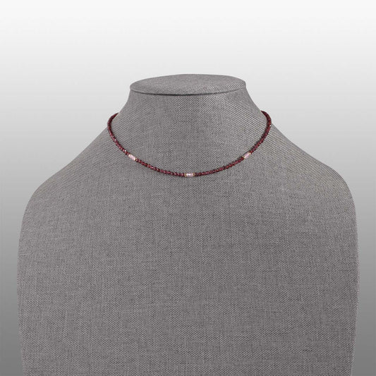 garnet and pink zircon faceted bead with gold filled accents necklace front on grey textured necklace form