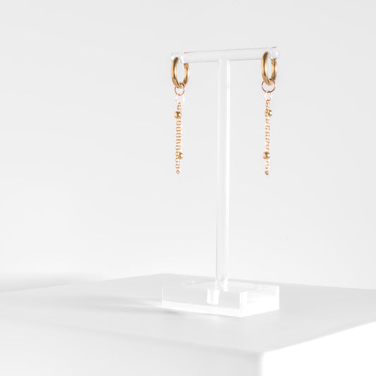 gold over stainless steel hoop earrings with satellite chain drops on clear acrylic earring stand