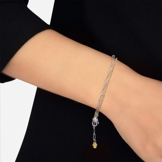 stainless steel paperclip and gold tone cable layered chain bracelet with gold hamsa charm and oversized stainless steel lobster claw clasp on model arm