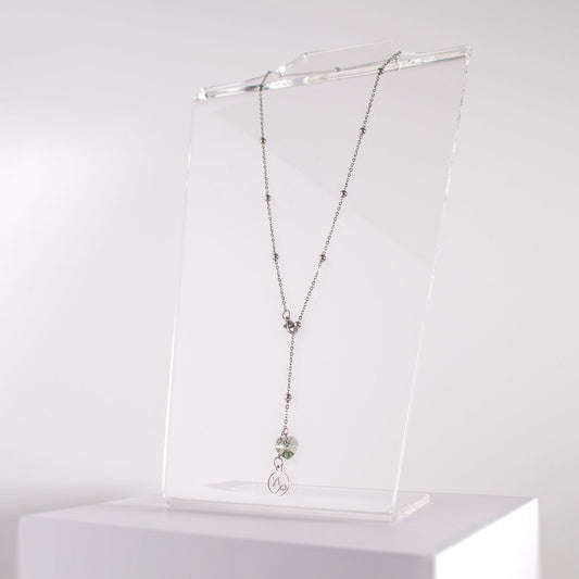 a stainless steel beaded station lariat necklace with a lobster claw clasp, Capricorn charm and black diamond crystal heart on a clear acrylic stand