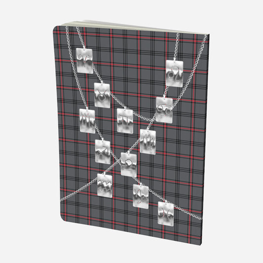 back cover of large notebook with silver zodiac tags on chains on a grey red and black plaid background