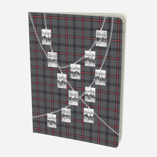 front cover of large notebook with silver zodiac tags on chains on a grey red and black plaid background