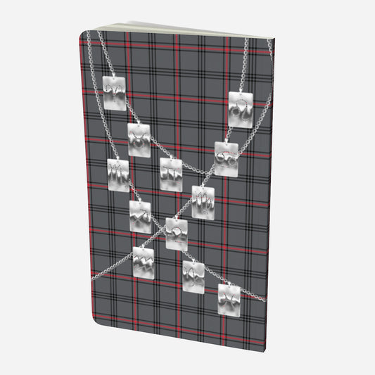 back cover of small notebook with silver zodiac tags on chains on a grey red and black plaid background