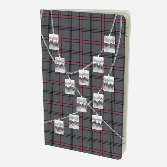 front cover of small notebook with silver zodiac tags on chains on a grey red and black plaid background