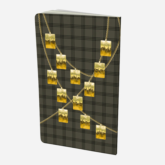 back cover of small notebook with gold zodiac tags on chains on and olive and black plaid background