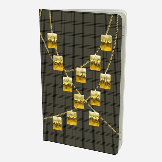 front cover of small notebook with gold zodiac tags on chains on and olive and black plaid background